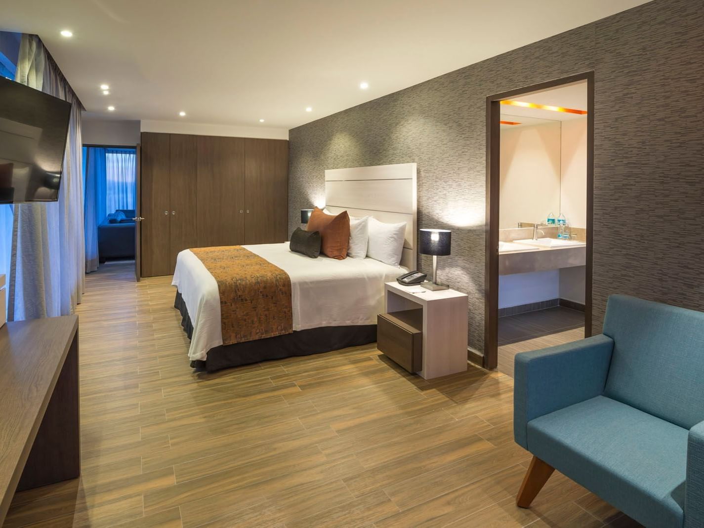 King Presidential Suite with a textured accent wall and an open doorway leading to the bathroom at Real Inn Celaya