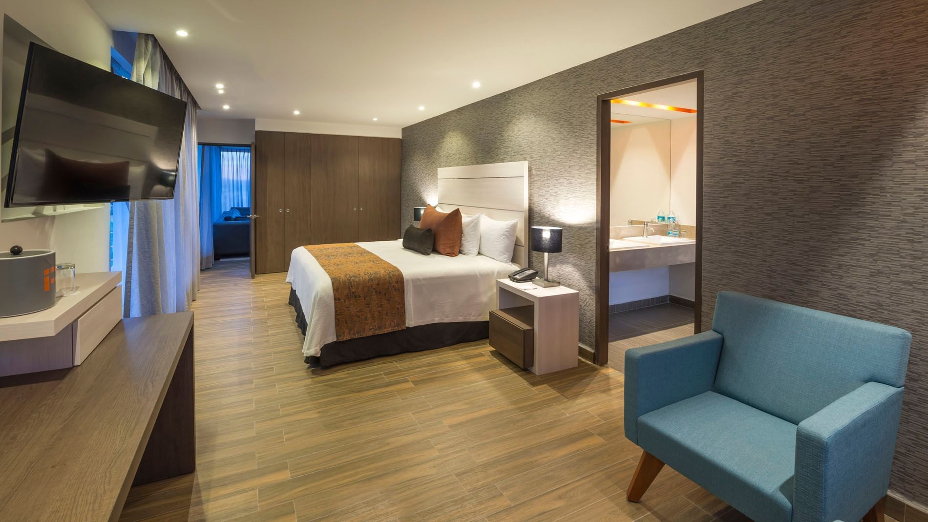 King Presidential Suite with a textured accent wall and an open doorway leading to the bathroom at Real Inn Celaya