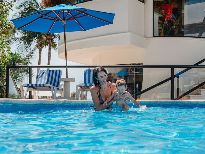 Lady playing with her son in the pool at The Reef Playacar