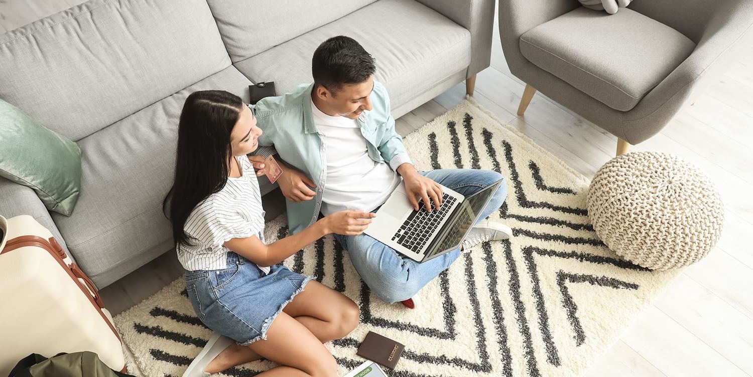 Two people looking at their laptops and smiling