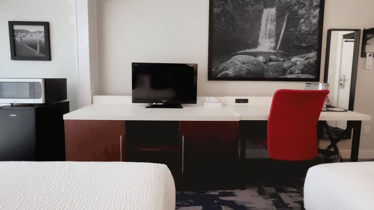 Guest room with two king beds, large desk, tv, chair, microwave, fridge