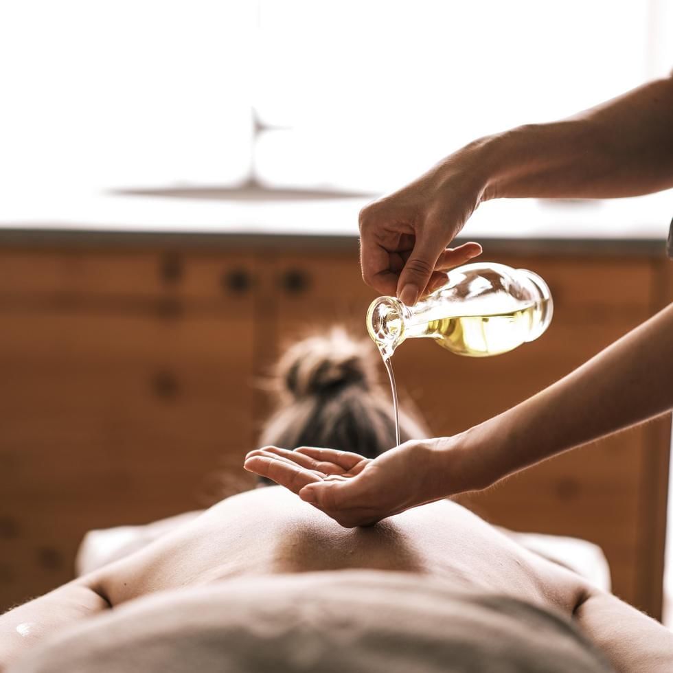 A person is receiving a massage with oil poured onto their back.