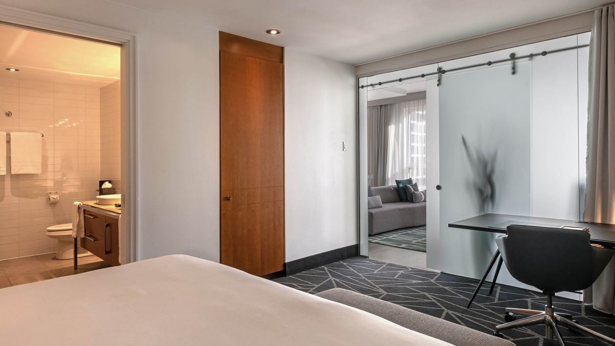 Intérieur du Penthouse Crescent avec lit, bureau et salle de bains au Warwick Le Crystal – Montréal.
