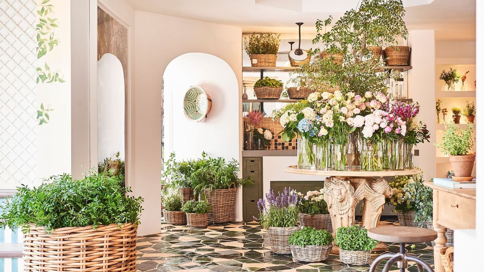 Interior of a bright flower shop with a round table placed on a tiled floor near an arched doorway at Marbella Club