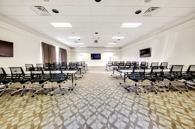 Classroom-style Senate room with tables, ergonomic chairs, and dual screens at Heritage Hotel