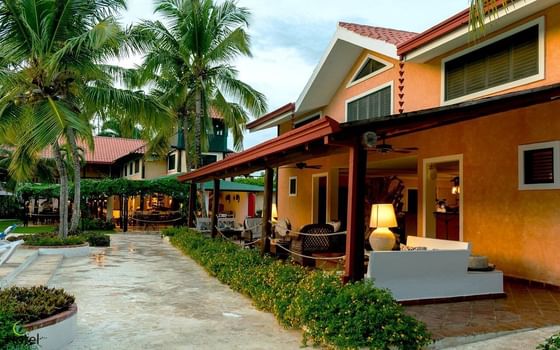 Tropical-style buildings at The Hub Hotels in Higuey, Dominican Republic, featuring palm trees and an outdoor patio