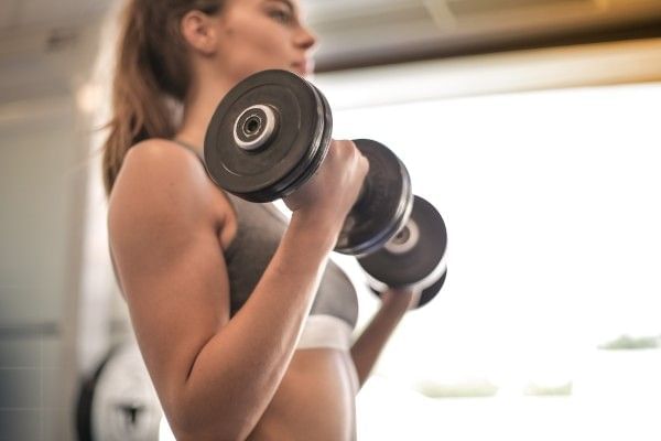 Woman performing bicep curls with dumbbells during a workout.
