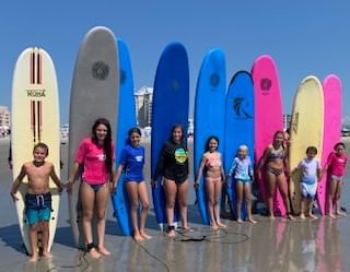 Kids all line up with their boards for surf lessons in Diamond Beach, NJ, near ICONA Diamond Beach