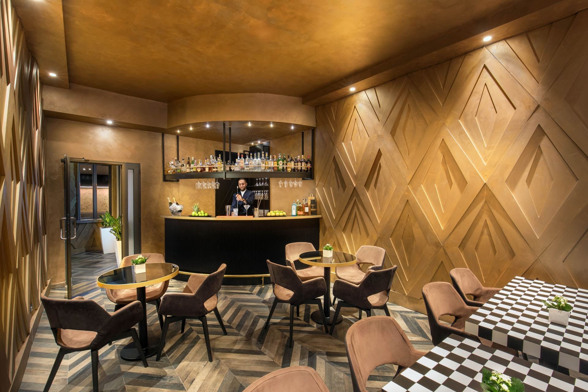 Bartender behind the counter in Lounge Bar with a warm ambience and tables at The Style