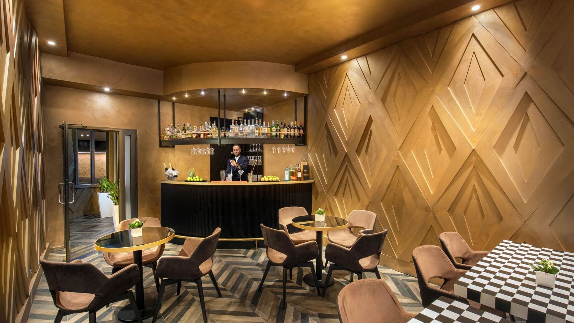 Bartender behind the counter in Lounge Bar with a warm ambience and tables at The Style
