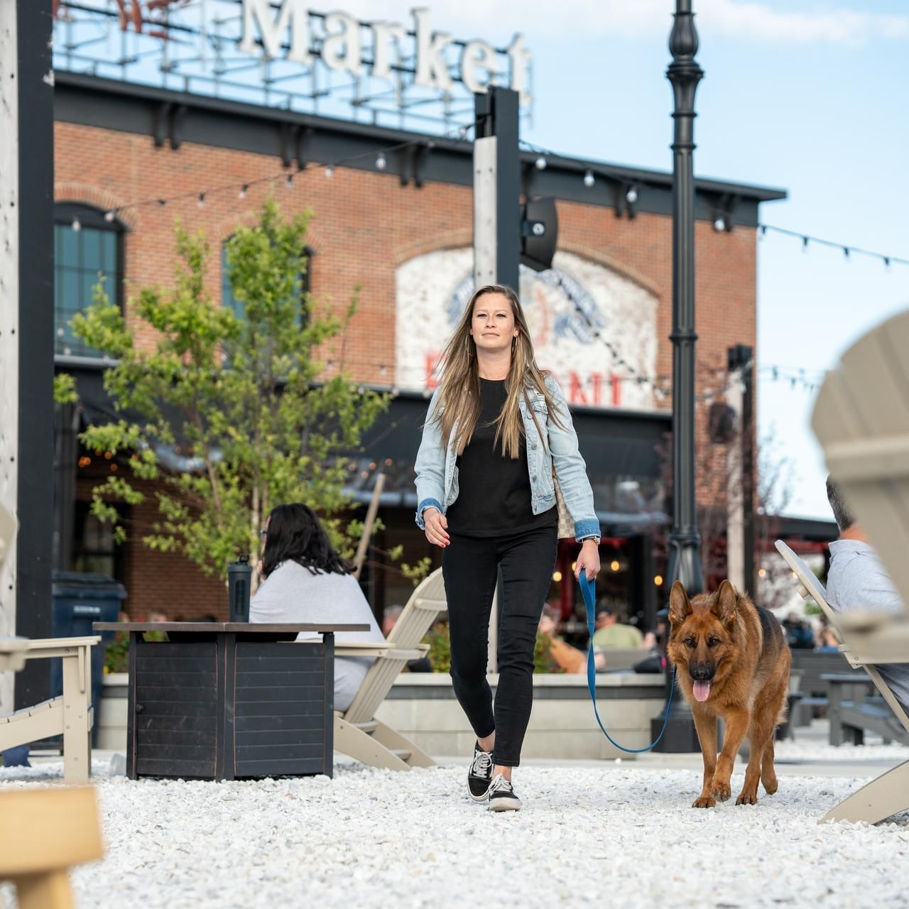 Woman walking a German Shepherd dog in Beer Garden near The Artisan Hotel at Tuscan Village