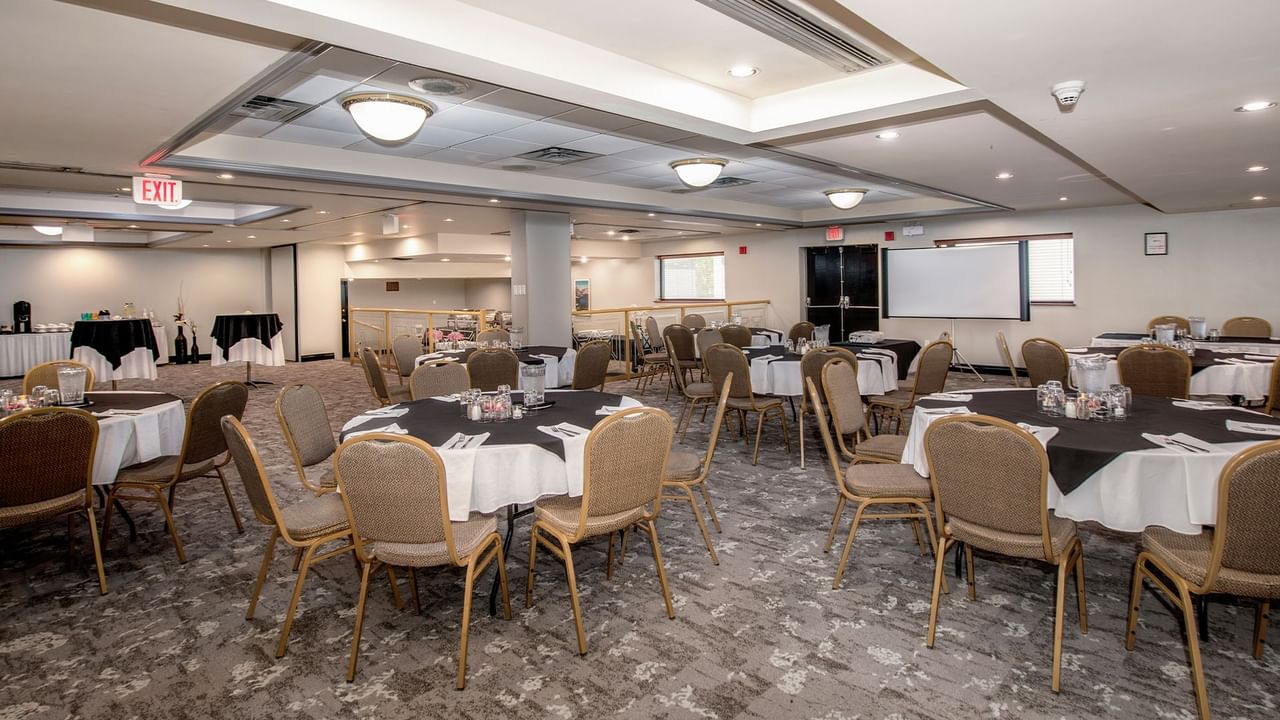 Banquet room with round tables, chairs, and a whiteboard, set up for an event.
