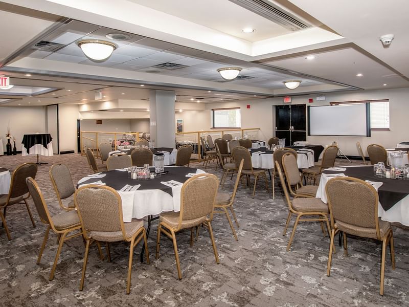 Banquet room with round tables, chairs, and a whiteboard, set up for an event.