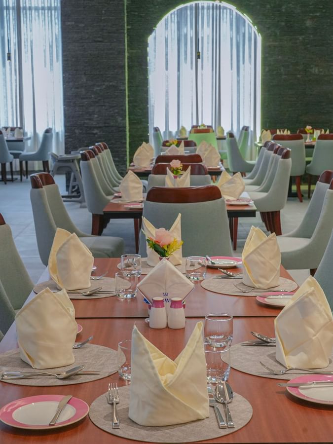 Neatly set dining tables with napkins and cutlery at Almir Restaurant in Jeddah at Warwick Hotel & Spa.