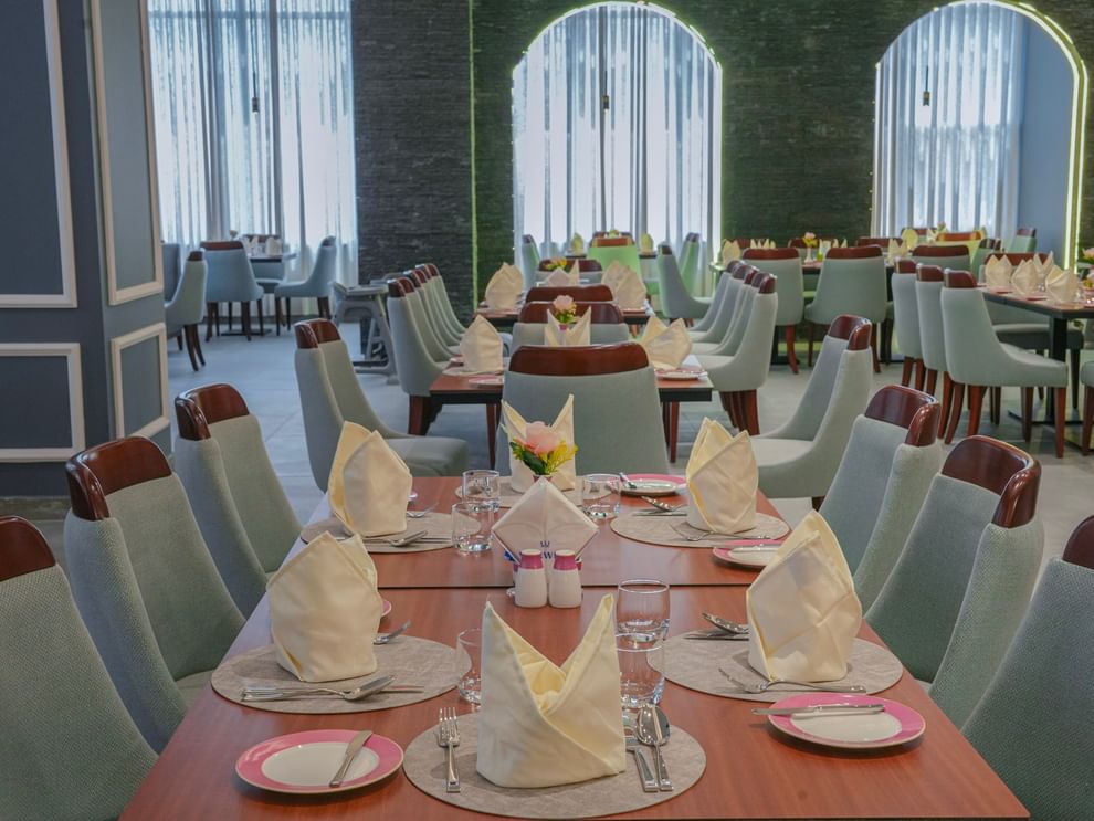 Neatly set dining tables with napkins and cutlery at Almir Restaurant in Jeddah at Warwick Hotel & Spa.