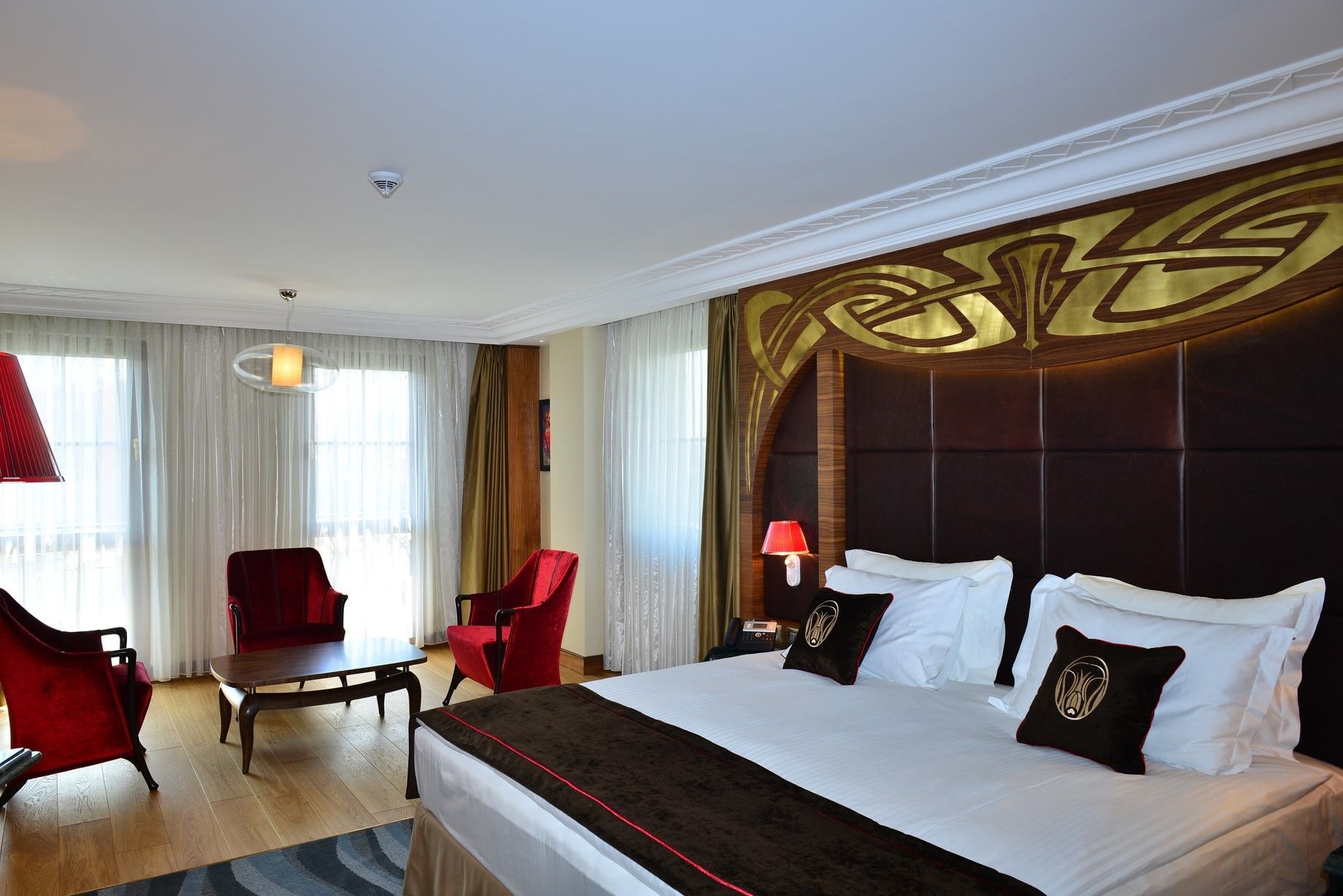 Red velvet chairs by a small table surrounding a bright window in Deluxe Room at Warwick Ankara