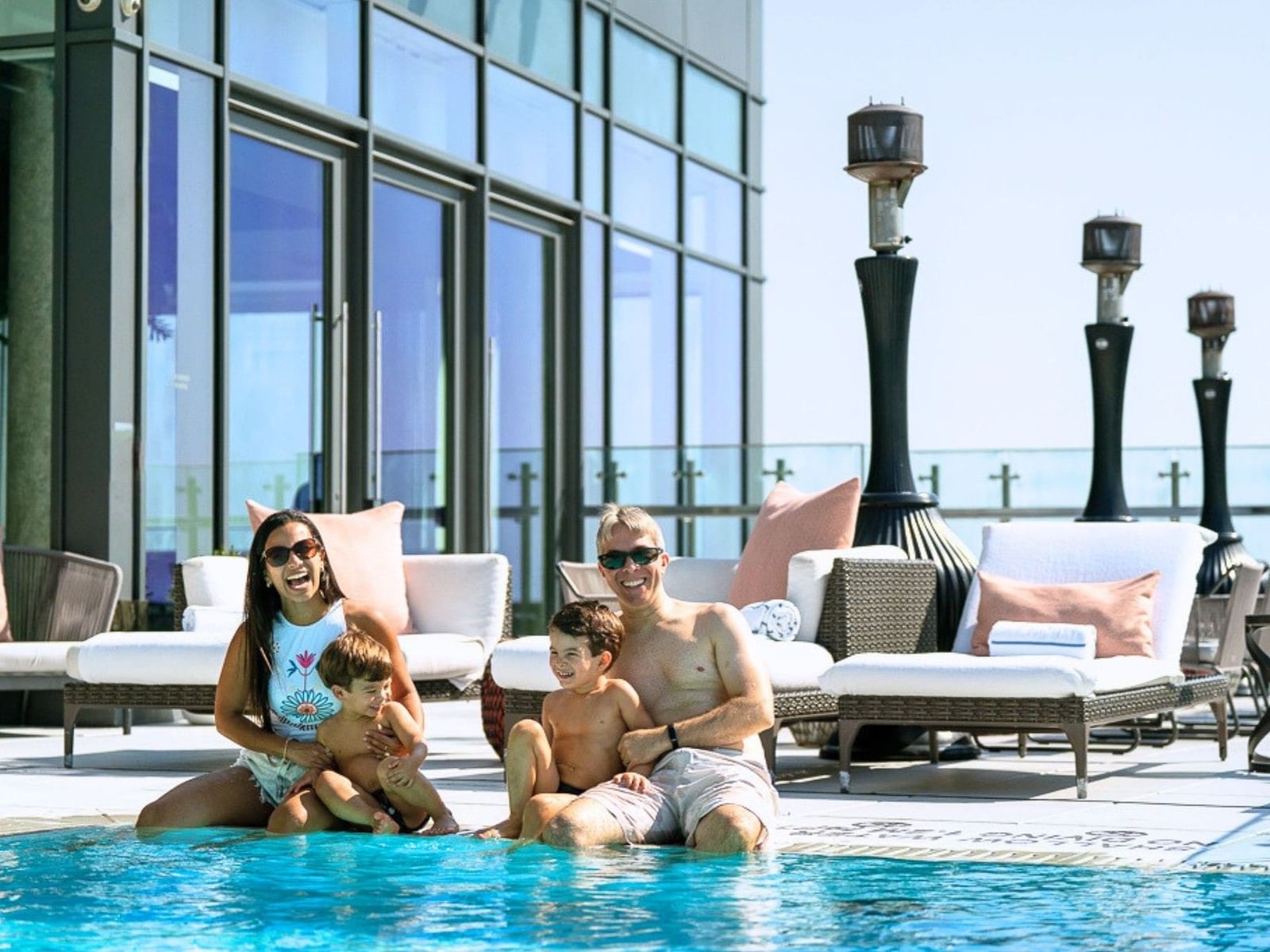 Family relaxing by Hotel x Toronto pool with patio and large windows in the background