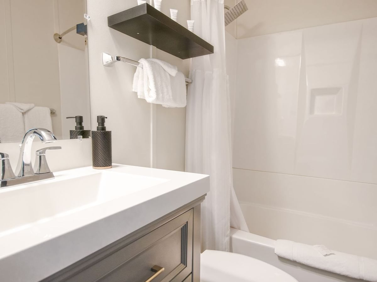 Hotel washroom with toilet, bathtub, sink, towels, and soap