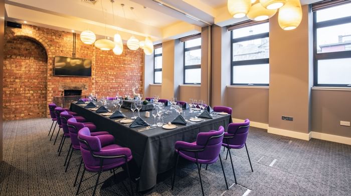 A hall prepared for a meeting with a black table set with cutler