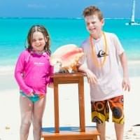 Two kids posing with a sea shell at Somerset on Grace Bay