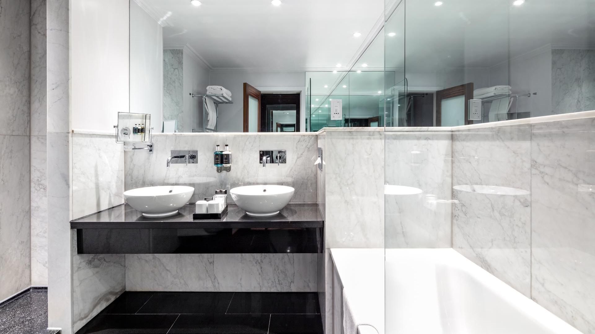 Modern bathroom in the Collection Premium Room at The May Fair Hotel featuring double sinks, mirrored wall, and bathtub