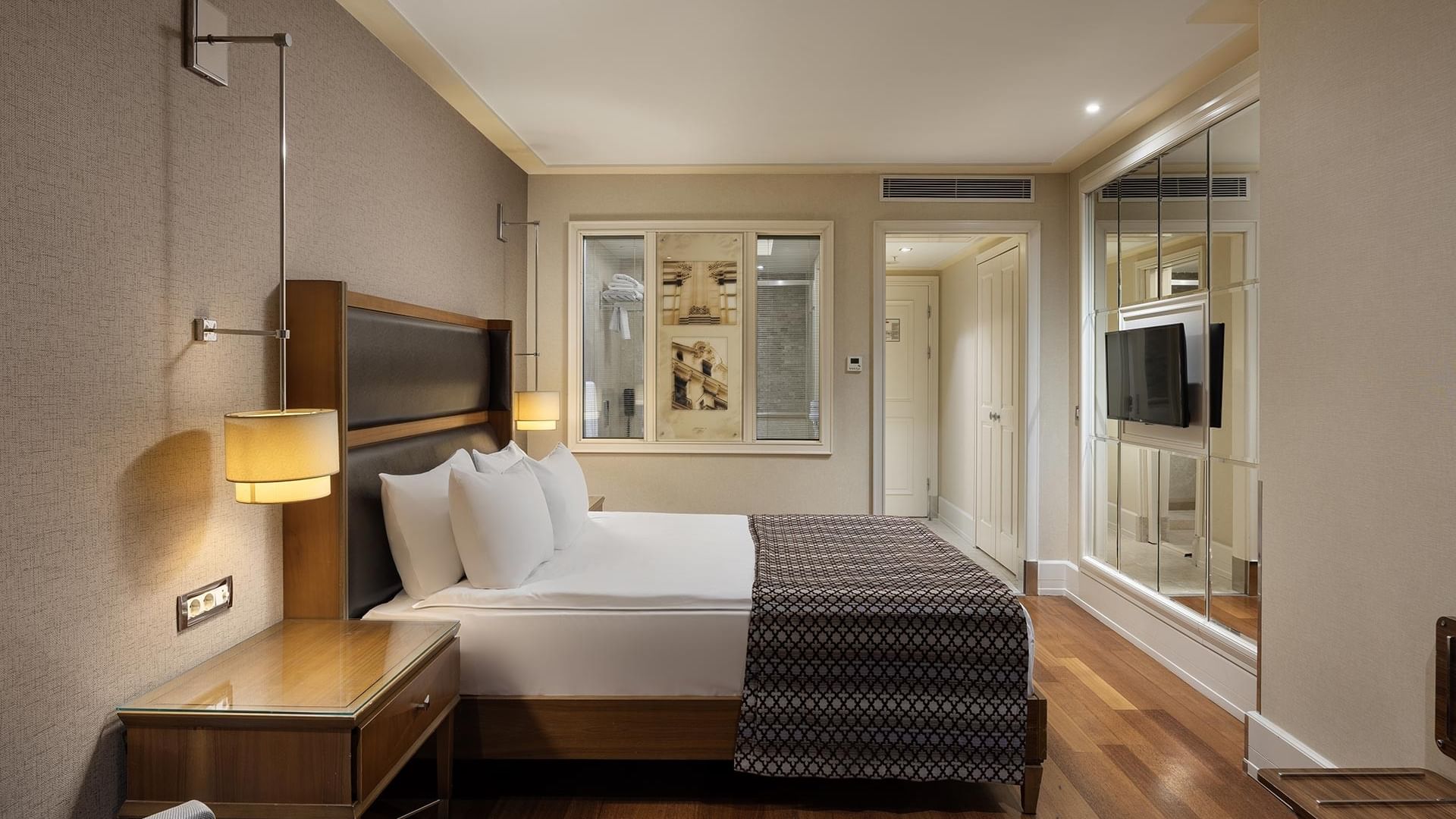 Titanic City Taksim’deki Superior odanın içi, büyük yatak, lambalar, masa ve televizyon içerir.