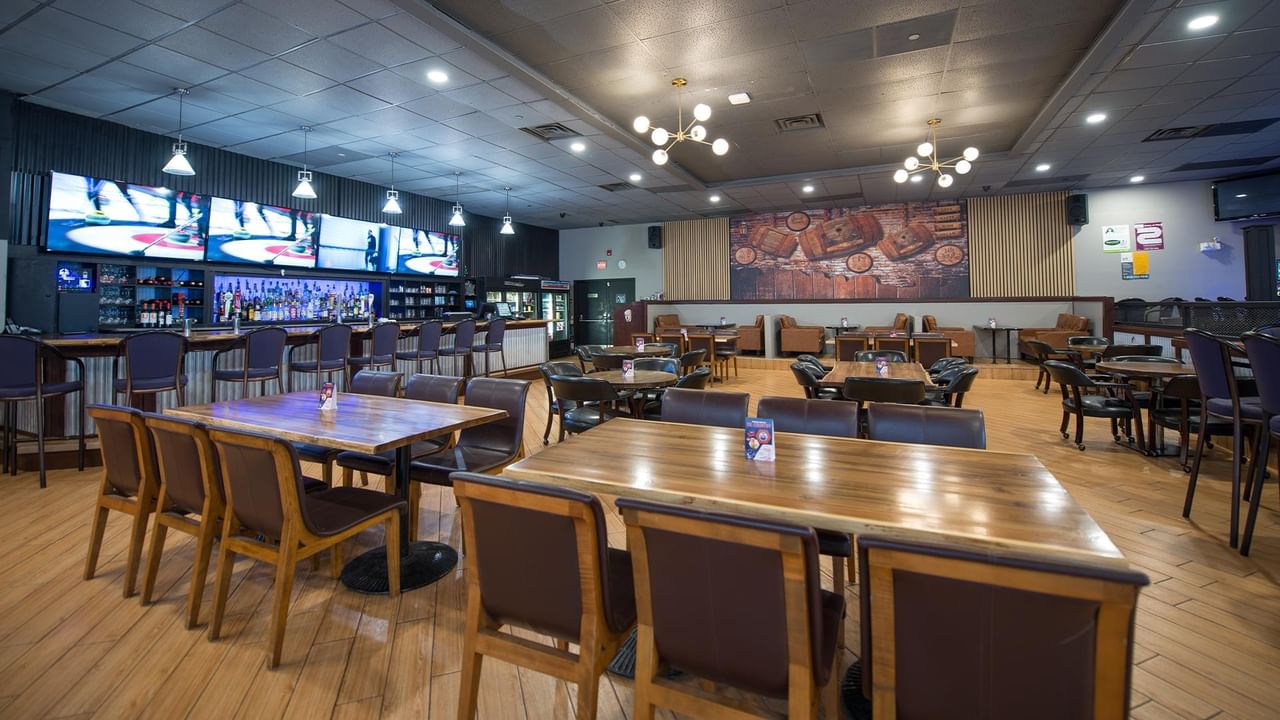 Interior of The Den Pub with tables, chairs, and a bar.