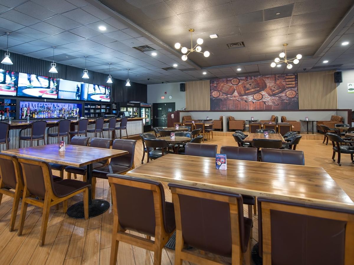 Dining area with wooden tables and chairs at The Den Pub.