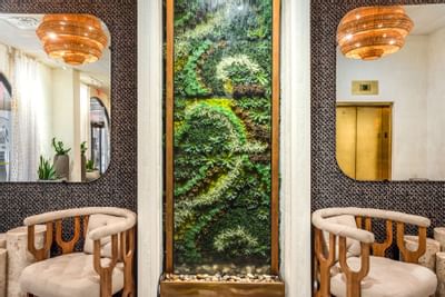 Stylish interior in lobby at The Riverwalk Plaza Hotel with wooden chairs, a lush garden display, and modern lighting