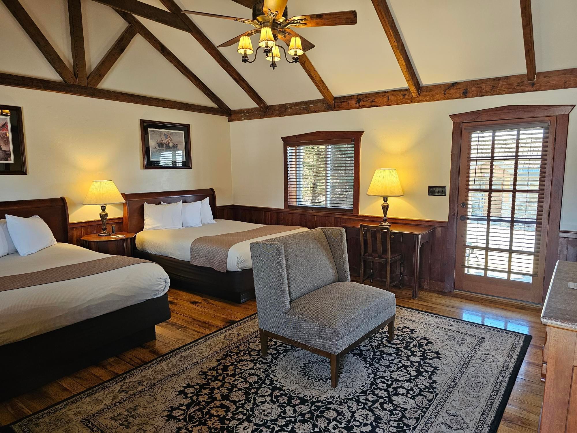Captain's Lodge cozy room with two queen beds, a chair, and wooden floors at The Lodges at Gettysburg hotel in PA.
