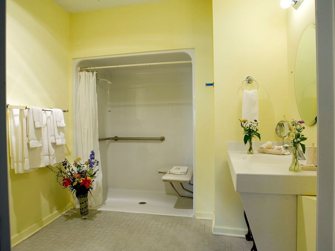 ADA accessible bathroom with roll-in shower, shower chair, and grab bars