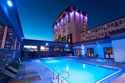 Pool area with lights at night in Carriage House Hotel