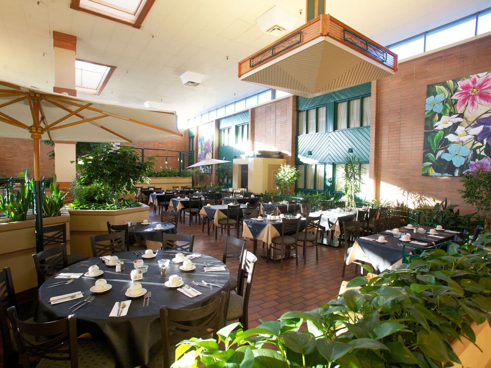 Table arrangements with culinary and plant decor in Garden Court Restaurant at The Glenmore Inn & Convention Centre