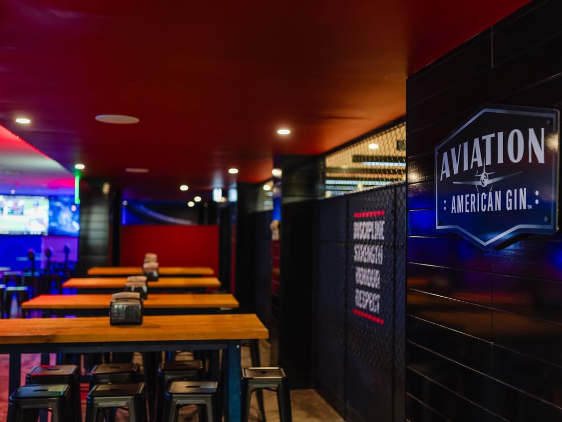 Interior view of the KG Sport Bar featuring wooden tables and a branded sign at Mercure Brisbane King George Square