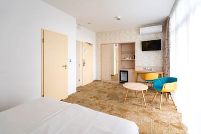 Executive Room with bed, two colorful chairs, work desk and TV at Metropol Hotel