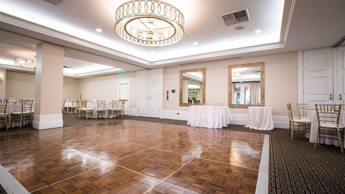 Courtyard Ballroom at El Prado Hotel, featuring a polished wooden dance floor and elegant round tables
