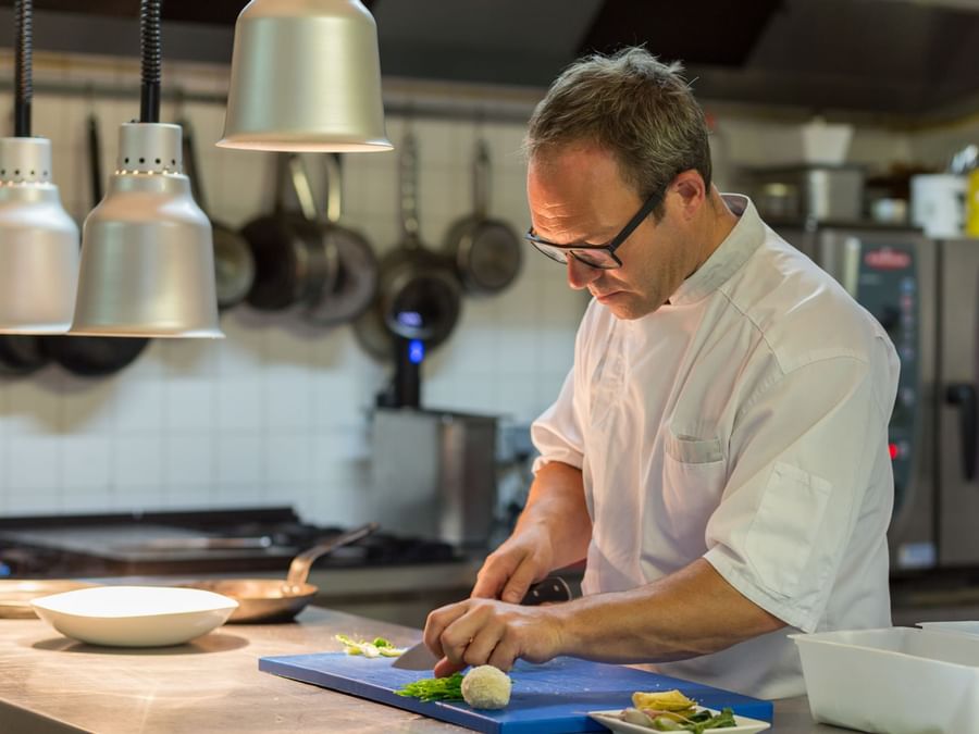 A chef preparing food in the kitchen of La Ferme des Mares