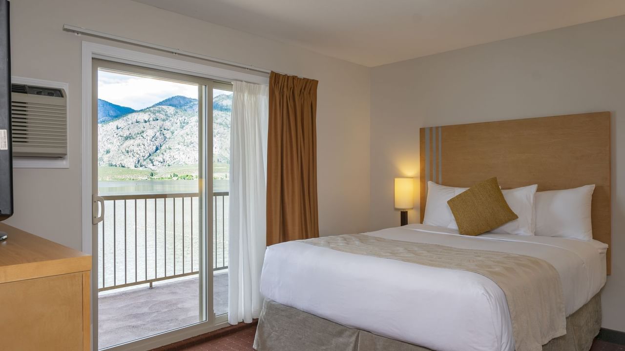 Bed in hotel room with balcony and view of lake