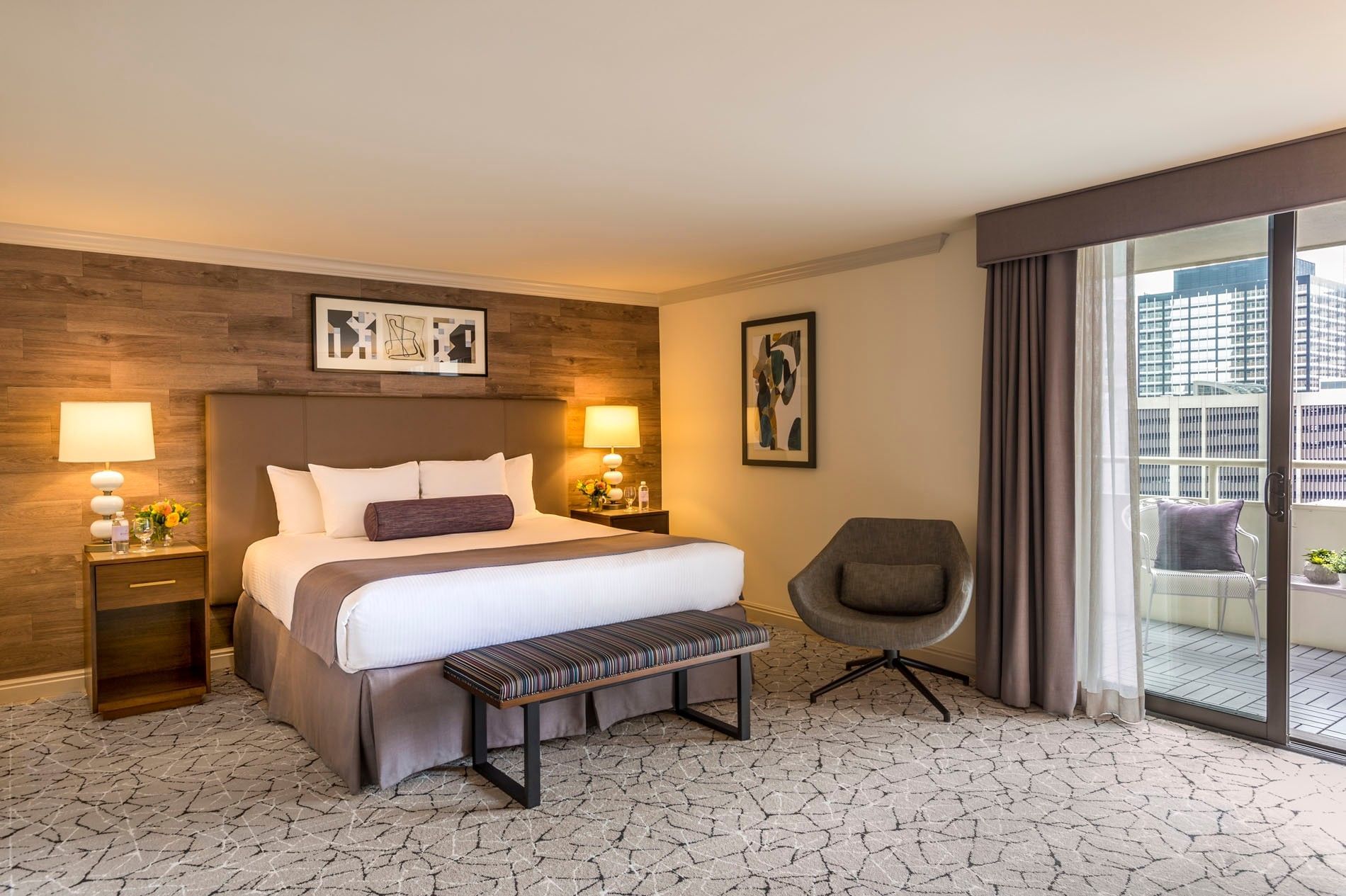 King bed by a grey swivel chair under a wood wall in Accessible Classic Room at Warwick Denver