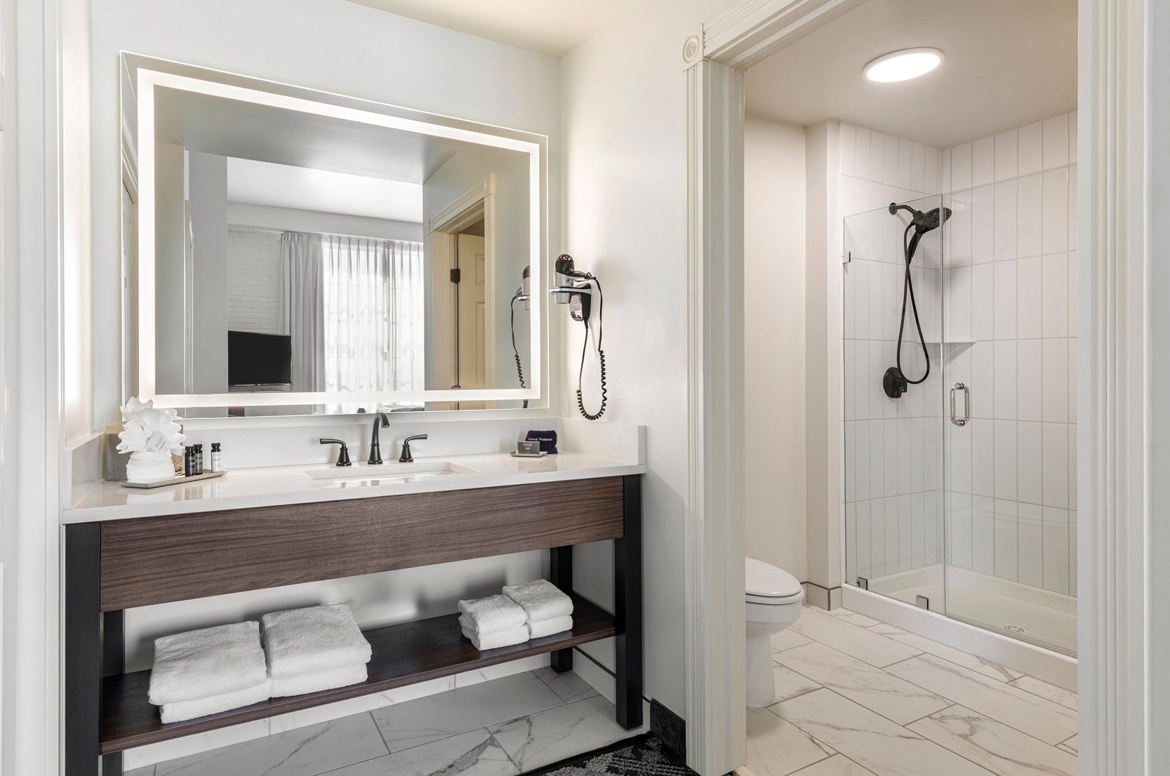 A modern bathroom with a double vanity, glass shower door, and white towels.