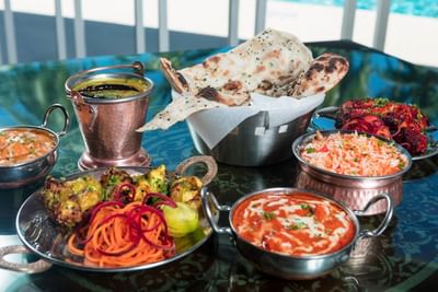 Variety of Indian dishes and bread served in metal bowls on a table at All Seasons Resort Europa