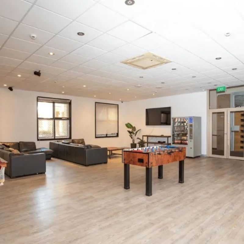 Cozy lounge area with pool table, couches, and foosball table in a university college.