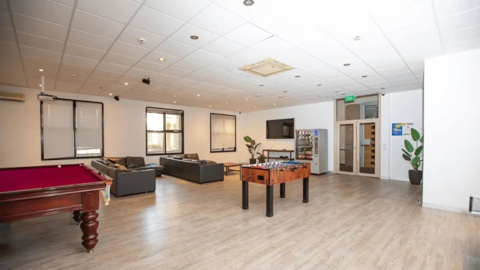 Cozy lounge area with pool table, couches, and foosball table in a university college.