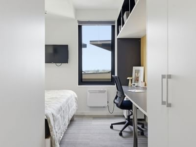Modern room with bed, desk, chair, and large window at UniLodge Auckland City.