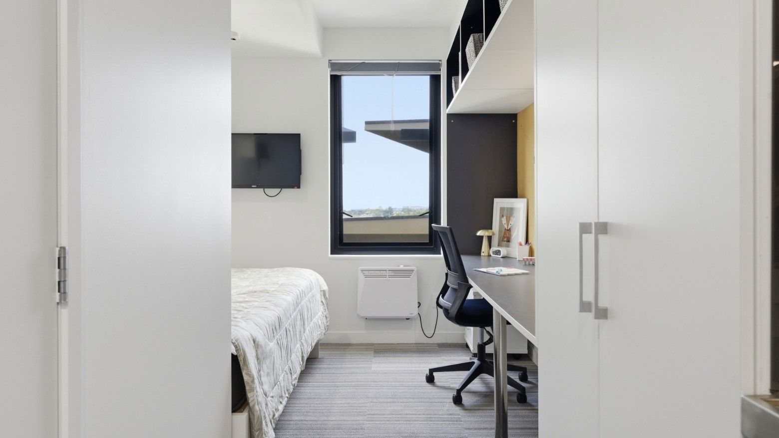 Modern room with bed, desk, chair, and large window at UniLodge Auckland City.