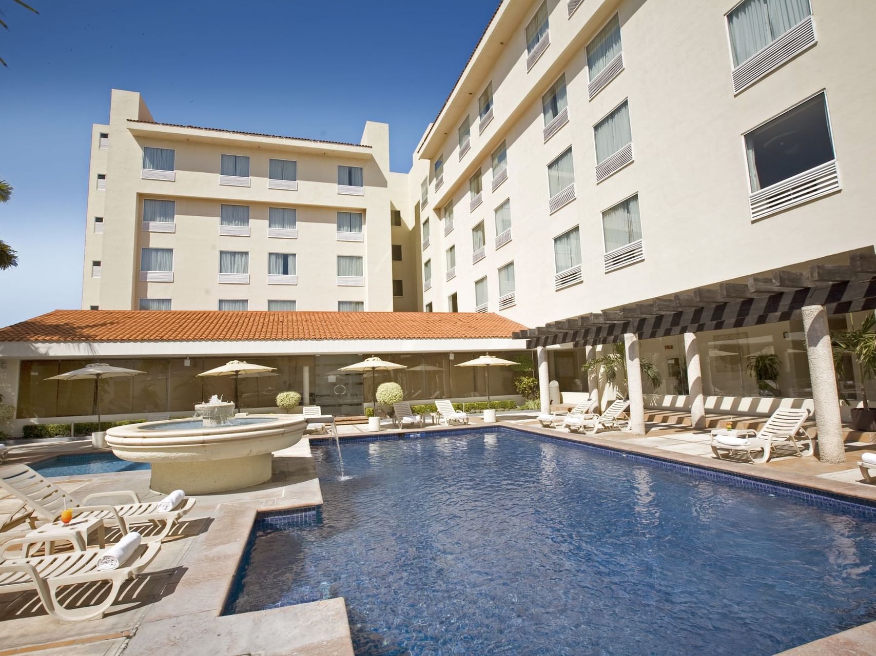 Outdoor Swimming pool with sunbeds at Fiesta Inn Hotels