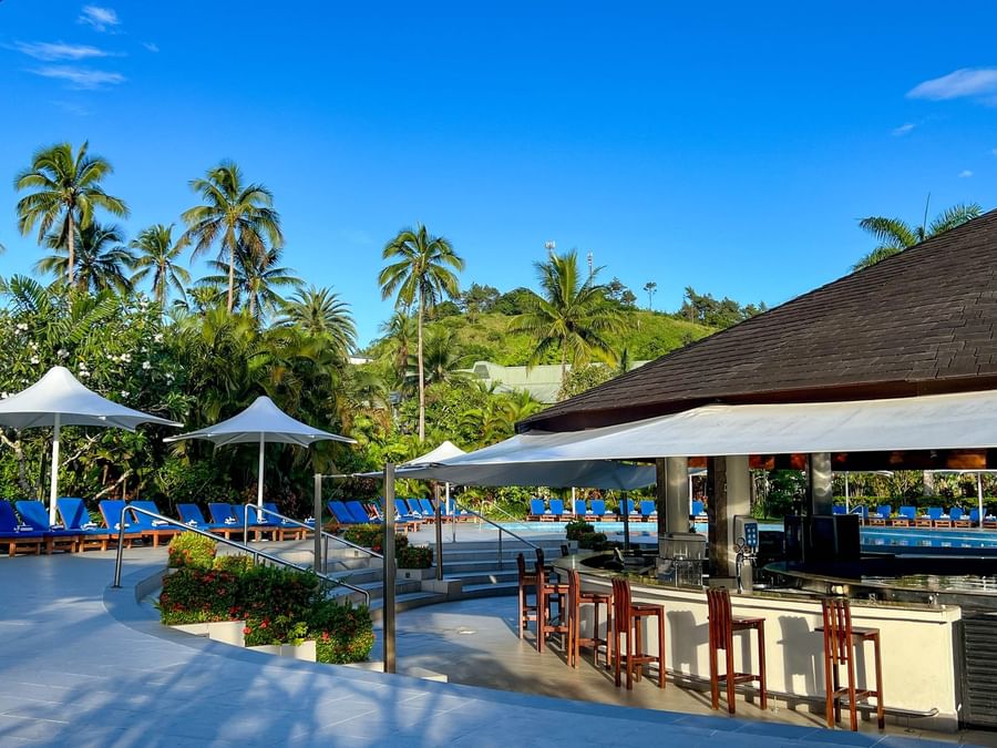 Resort pool area with bar and lounge chairs under umbrellas at The Naviti Resort - Fiji.