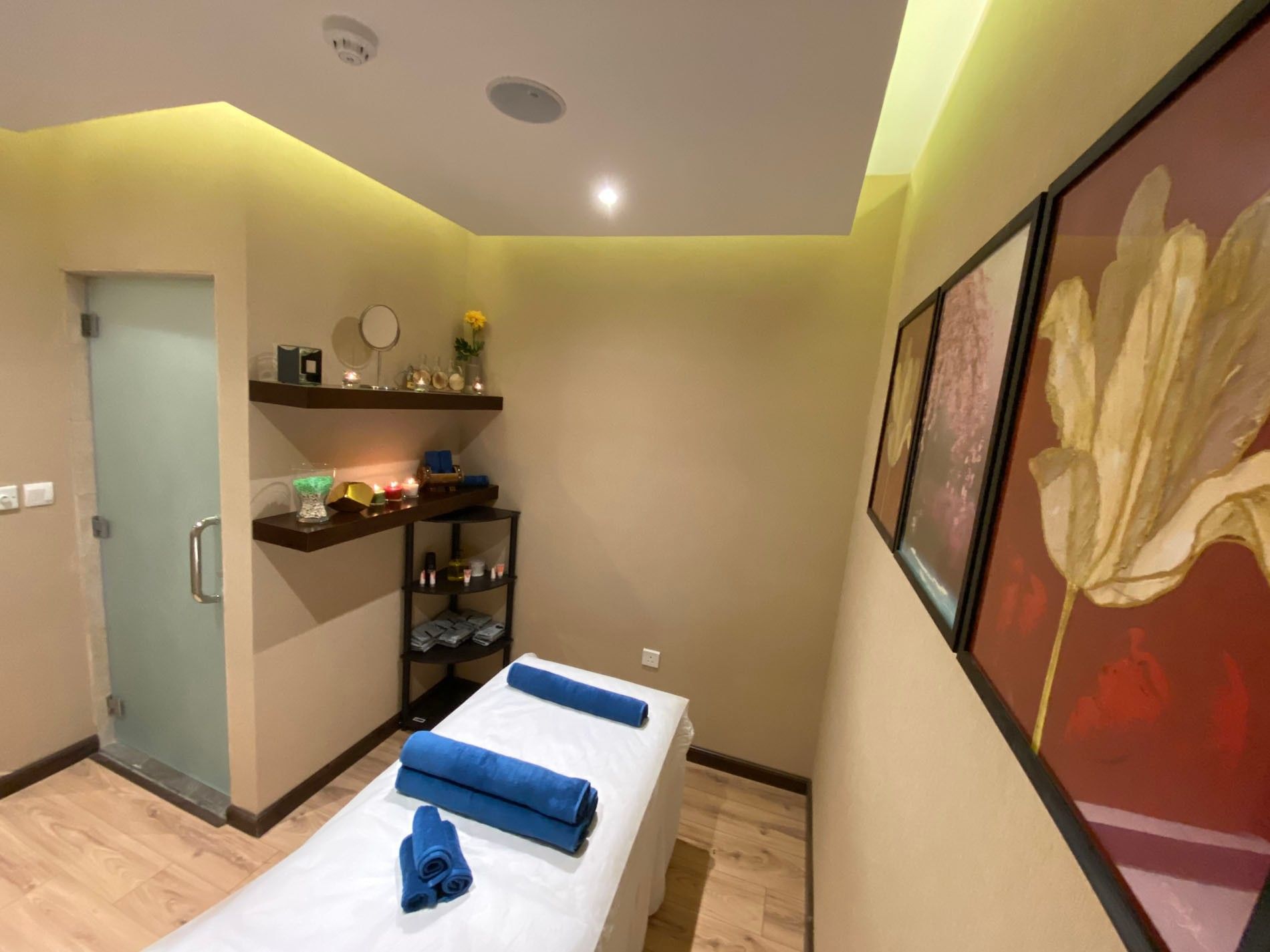 Massage table by blue towels under recessed lights in a Gold Spa at Naviti By Warwick Dammam