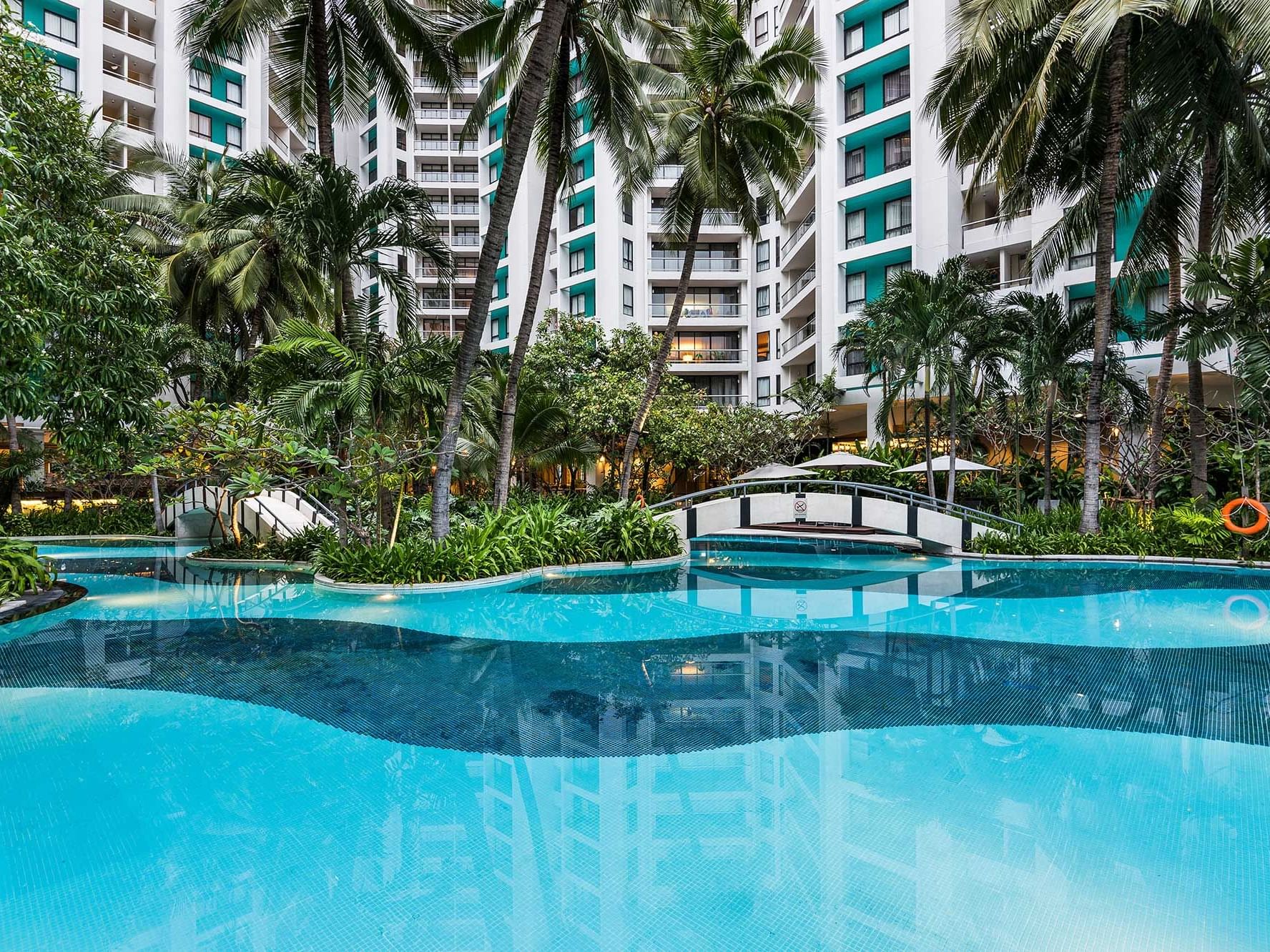 Outdoor pool area with palm trees at Chatrium Residence Sathon