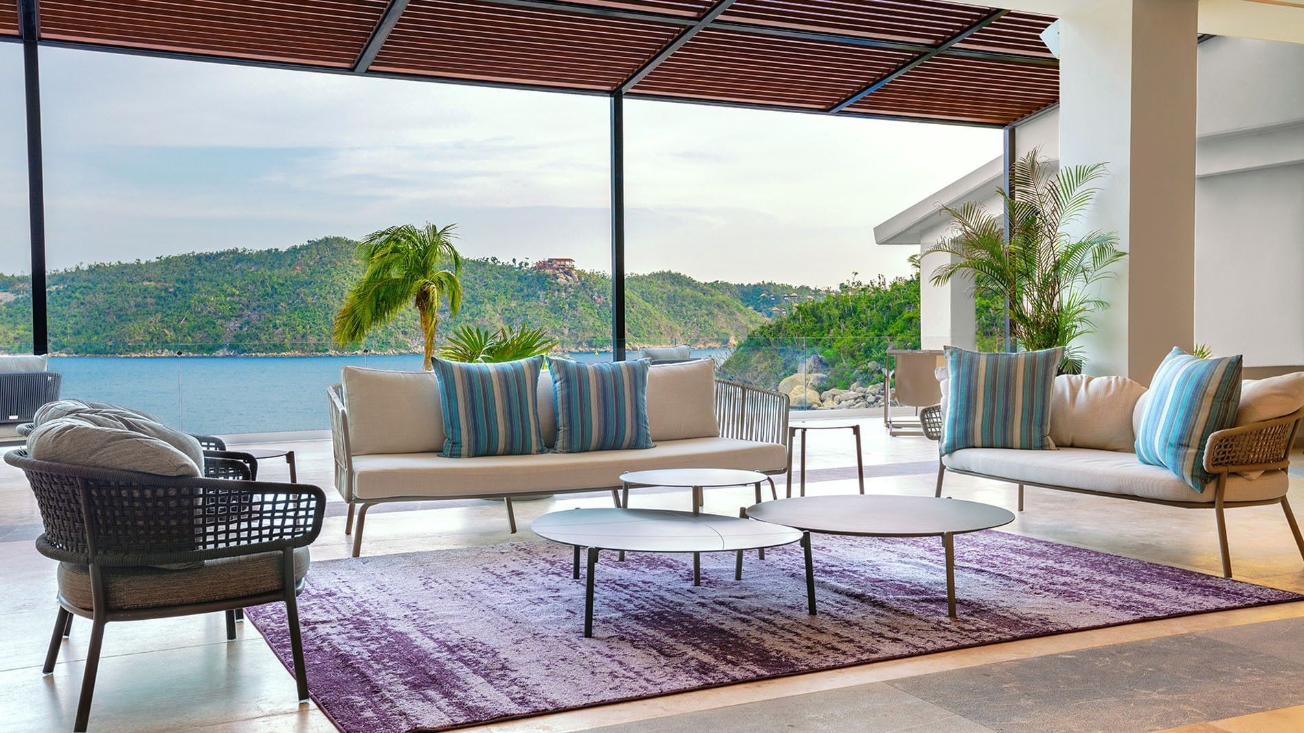 Modern open-air lobby lounge with blue striped pillows and ocean views at Camino Real Acapulco Diamante